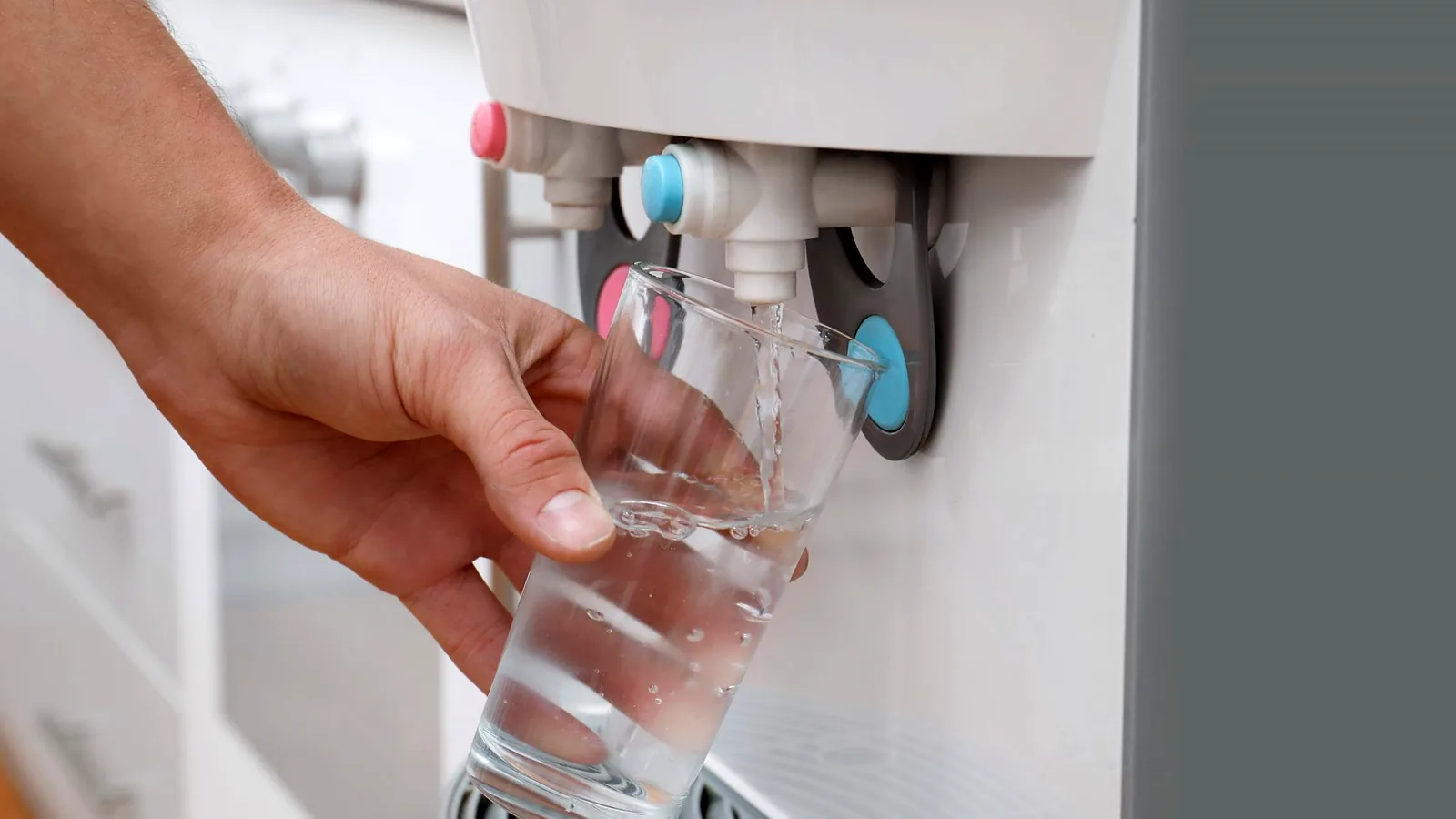 Persona llenando un vaso en un dispensador de agua