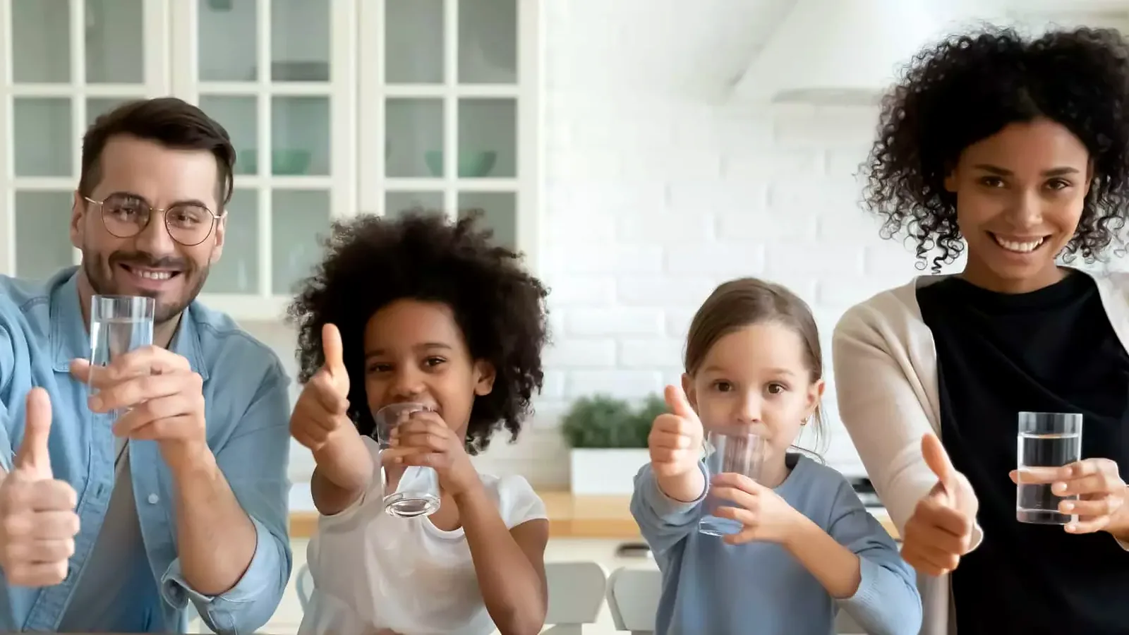 Familia feliz con vasos de agua purificada