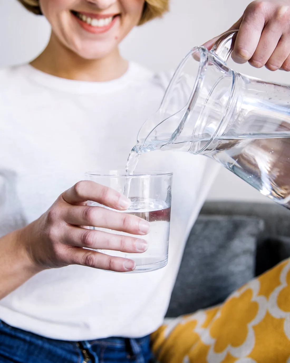 Mujer sirviendo un vaso de agua purificada en casa